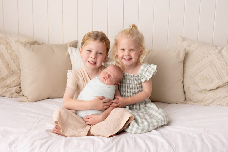 Siblings cuddling their newborn during a family newborn session