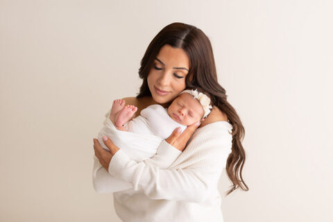 Mum cuddling her sleeping newborn daughter during a studio session